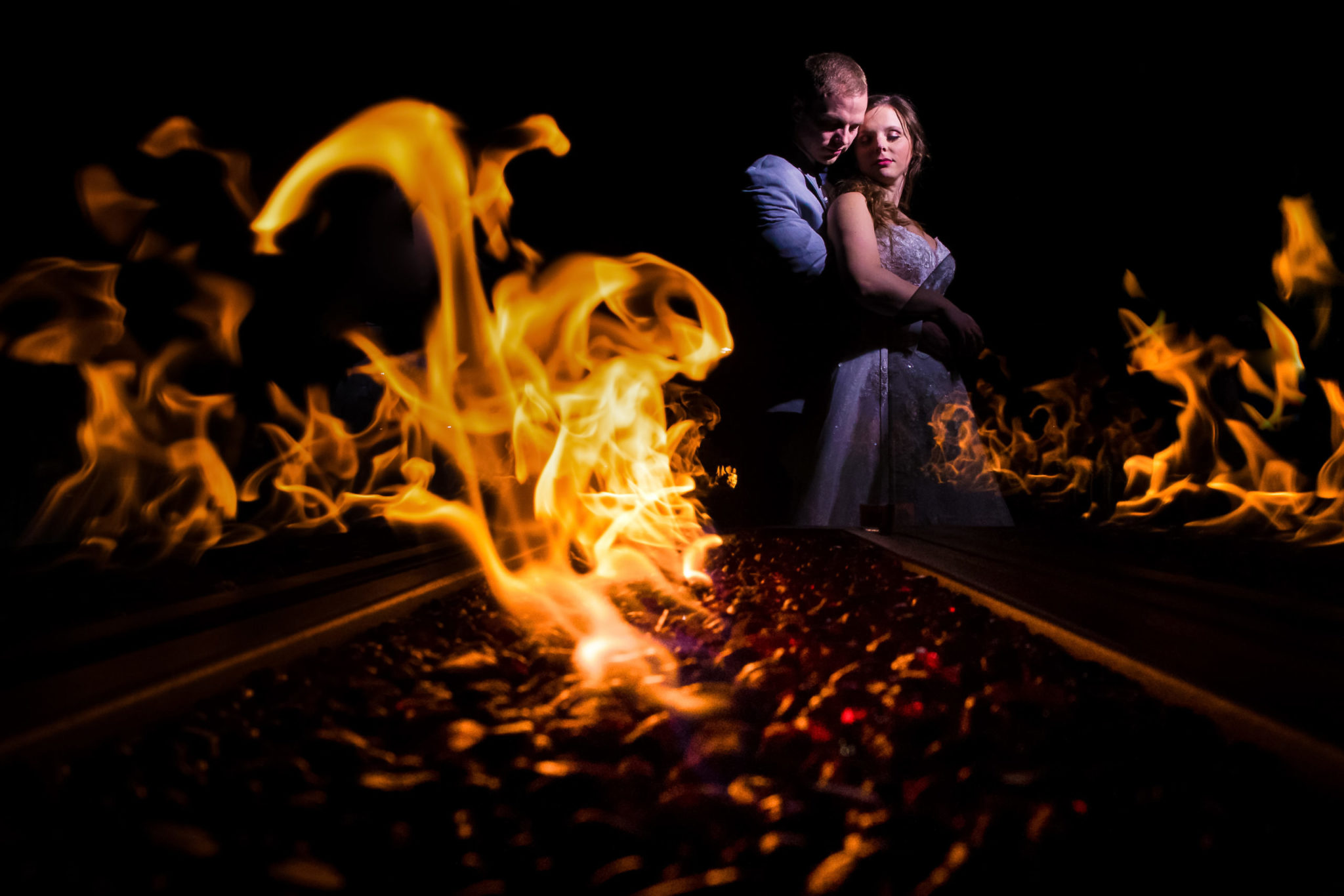 Creative NJ Wedding Photographer, Lisa Rhinehart, captures this creative, unique image of the couple embracing one another as the fire surrounds them outside of the Palace at Somerset Park