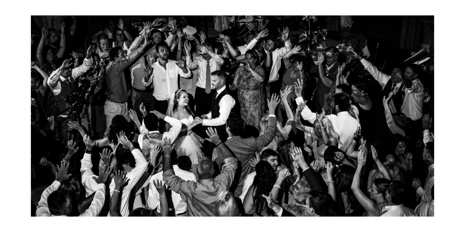 black and white image of the bride and groom as they dance with their guests and family during this palace at Somerset Park wedding reception 