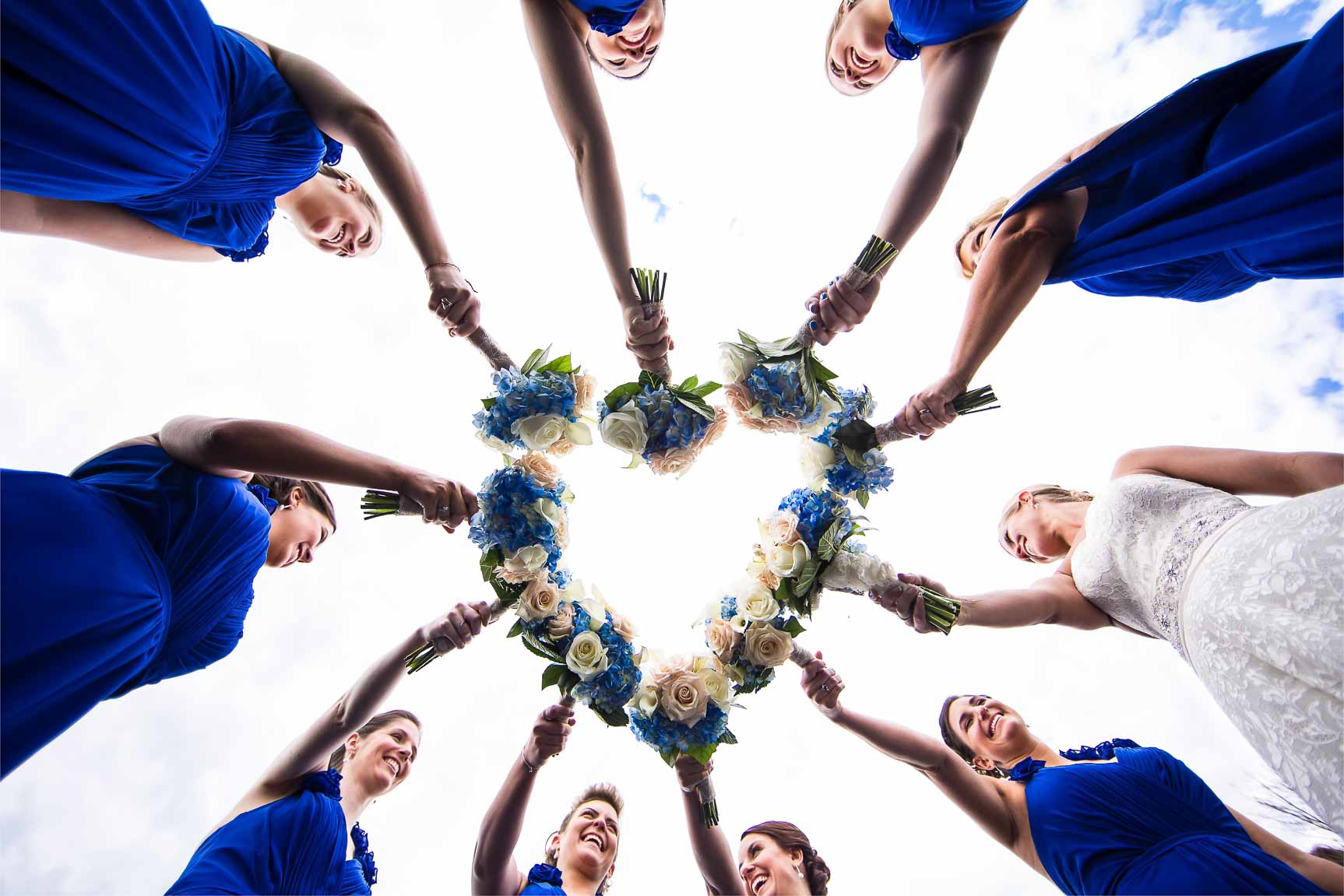 Creative PA Wedding Photographer, Lisa Rhinehart, captures this creative, fun image of the bride and her bridesmaids holding their bouquets in a heart shape 
