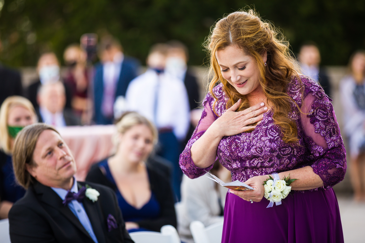 mother of the bride holds her heart as she reads during her daughter's wedding ceremony