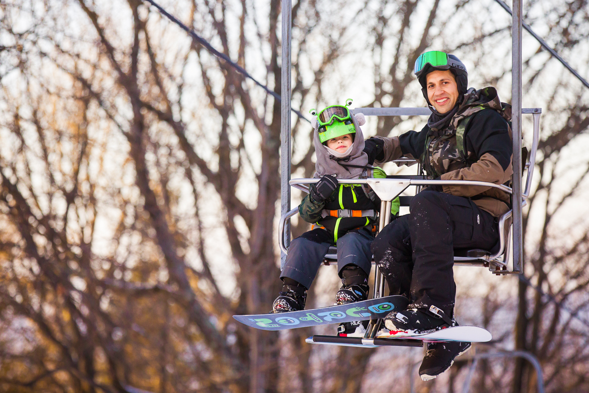 father and preschool child enjoy a ski lift ride at blue mountain resort 