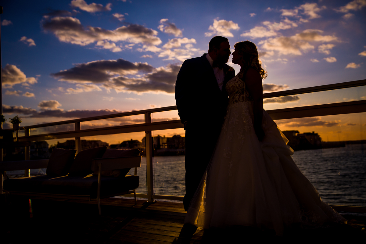 sunset wedding at reeds stone harbor bride and groom are silhouetted against blue and orange sky 