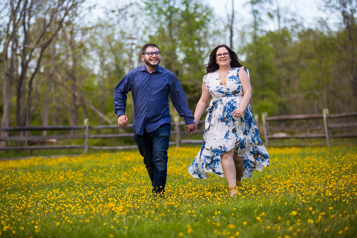engaged couple happy walks through field of blooming buttercups in Allaire state Park Engagement