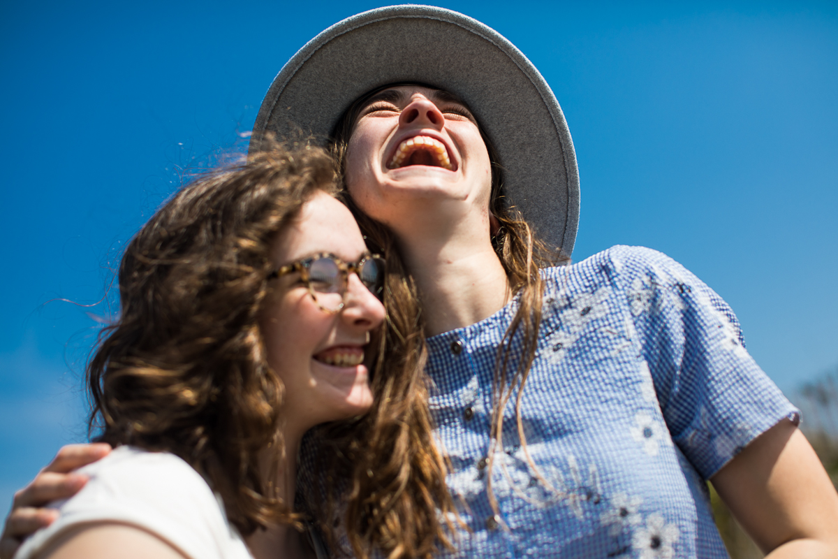 two sisters laugh against a blue sky family portraiture best award winning vacation photography 