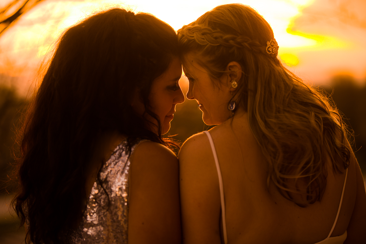 two brides looking at each other with sunset in the background