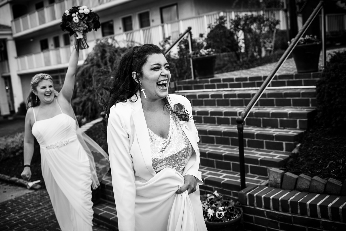 two brides laughing walking by each other black and white