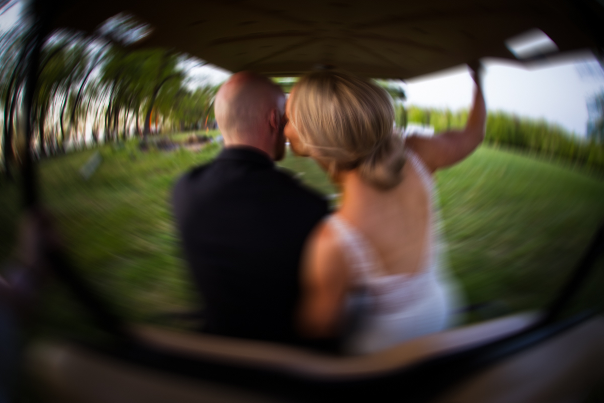 husband and wife riding on golf cart creative motion blur photographer Stevensville Maryland wedding