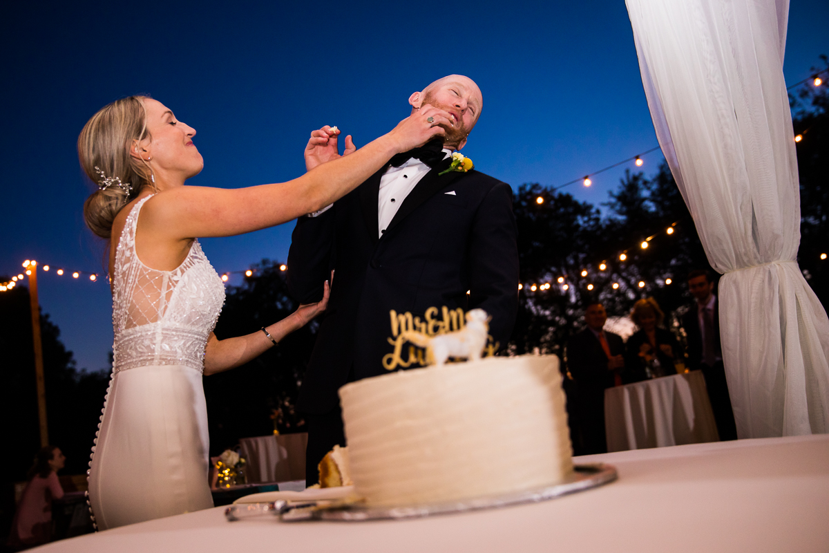 bride smashing cake in groom's face during cake cutting at Stevensville Maryland wedding venue