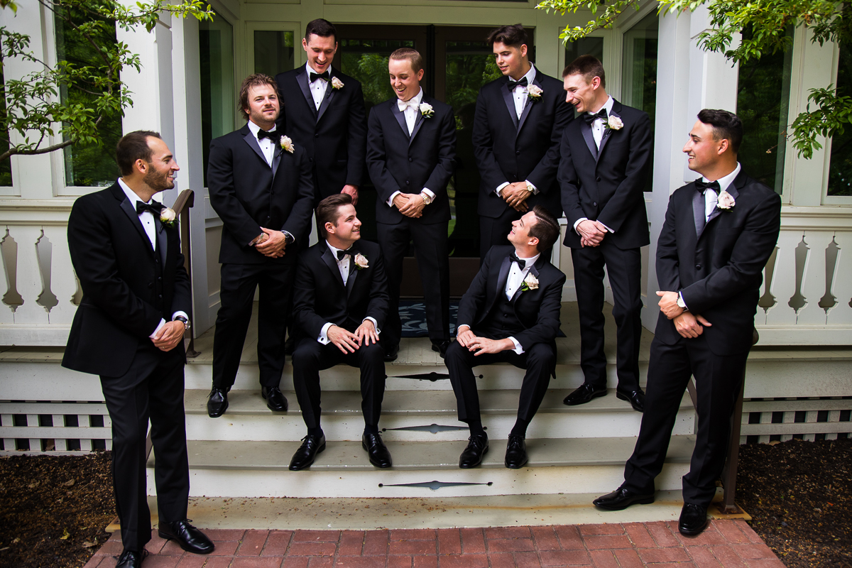 groom and groomsmen smiling and looking at each other standing on steps Omni Bedford Springs 