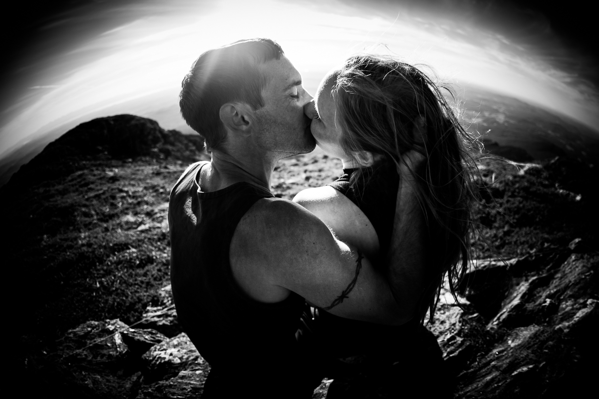 black and white fish eye lens photo of couple kissing on top of mount Mansfield with nature in background best award winning outdoor lifestyle photographer