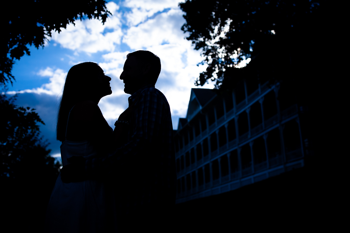omni Bedford Springs engagement photographer creative vibrant couple silhouetted against bright blue sky with omni resort in background