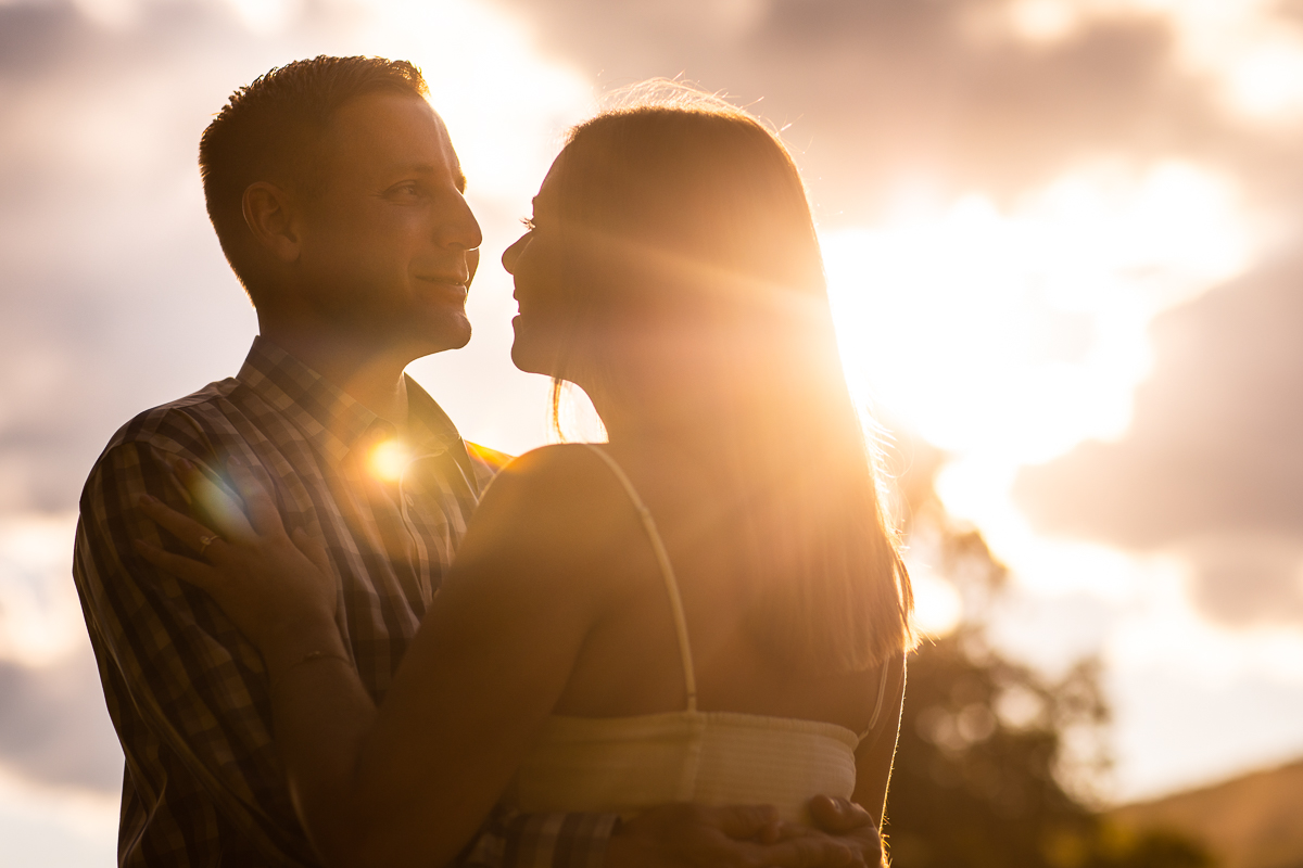 solar flare photography sunset sky couple standing looking at each other during engagement photos Bedford Springs pa