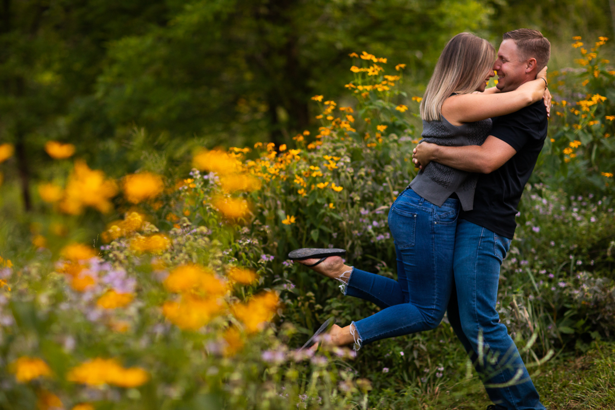 vibrant artistic creative engagement photographer central pa guy lifting girl up standing in field of wildflowers