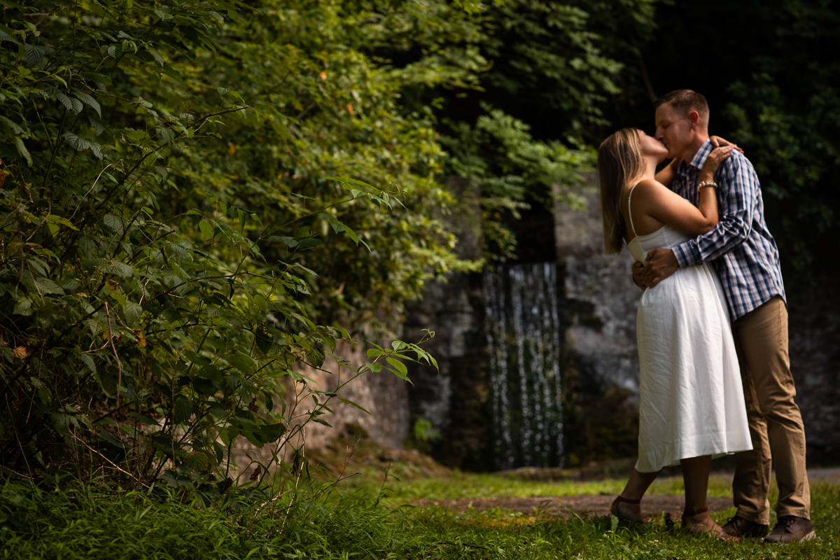 omni Bedford Springs wedding photographer couple kissing standing in front of waterfall framed by trees