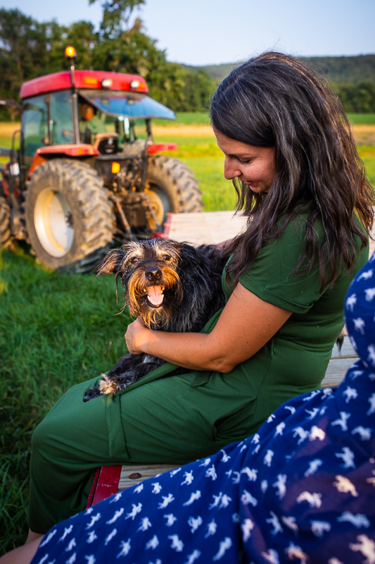 farm lifestyle photographer Carlisle pa woman holding dog on lap riding on flatbed being pulled by trailer at kings gap farm authentic candid