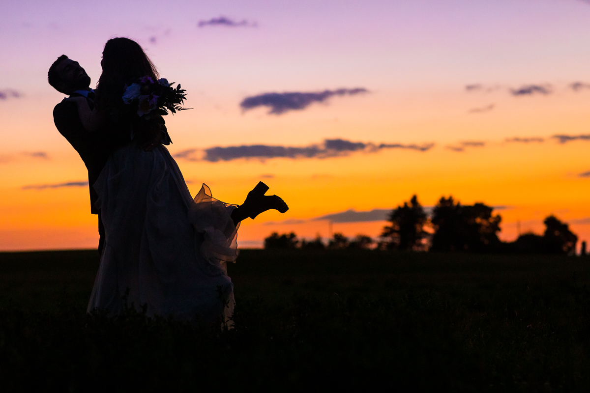 groom picking up bride wearing boots with wedding dress with beautiful sunset in the background best dc photographer