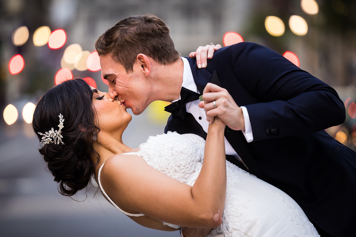 best award winning wedding photographer pa bride and groom kiss in downtown Philadelphia with street lights in background