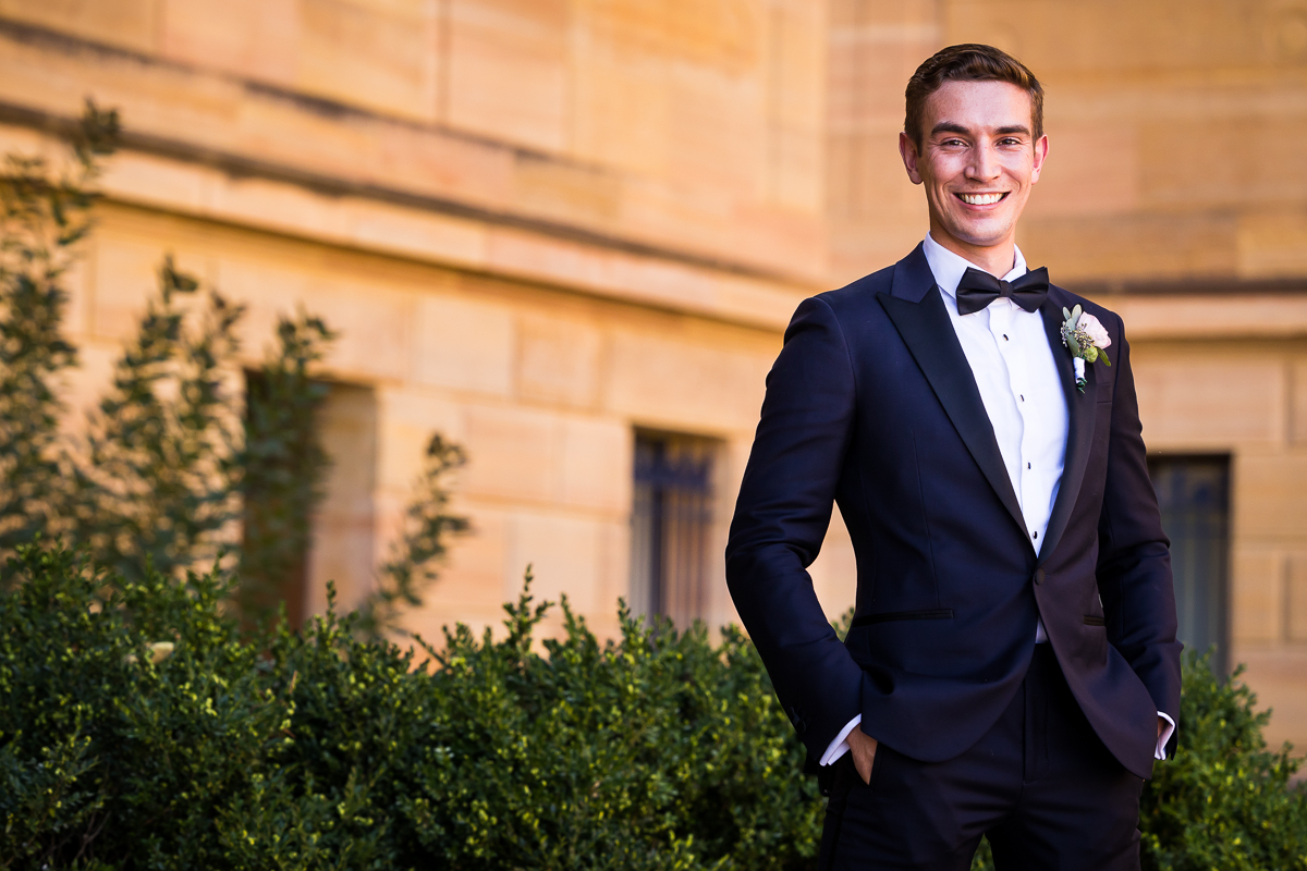 best authentic natural wedding photographer groom poses outside the Philadelphia museum of art