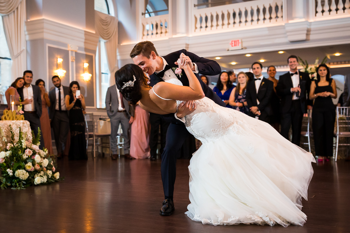 best award winning arts ballroom Philadelphia wedding photographer groom dips bride during first dance while guests smile in background