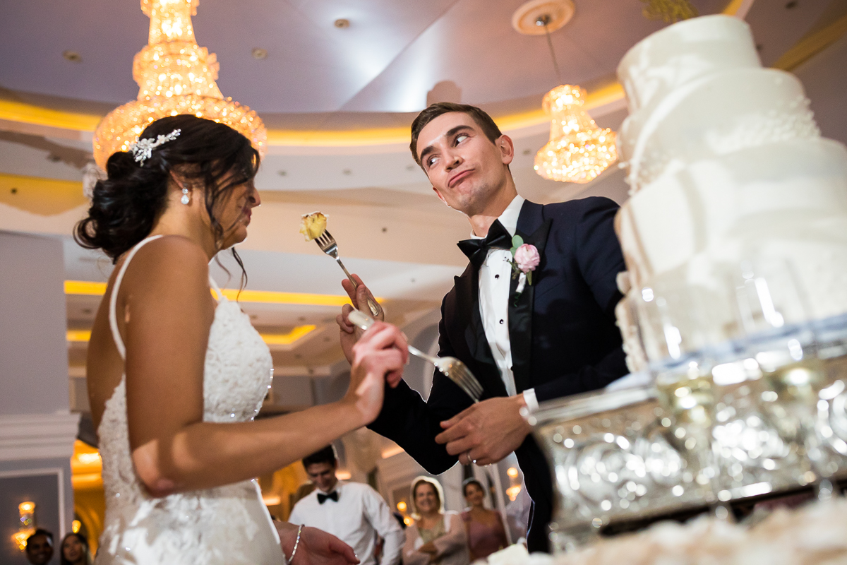 arts ballroom Philadelphia wedding reception bride and groom share first bites of cake together holding forks
