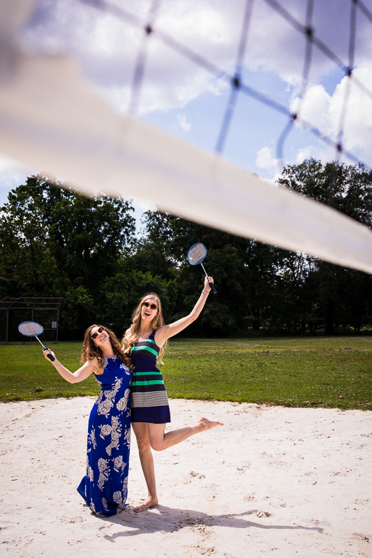 fun DC photographer two girls holding badminton rackets standing in sand on court outside