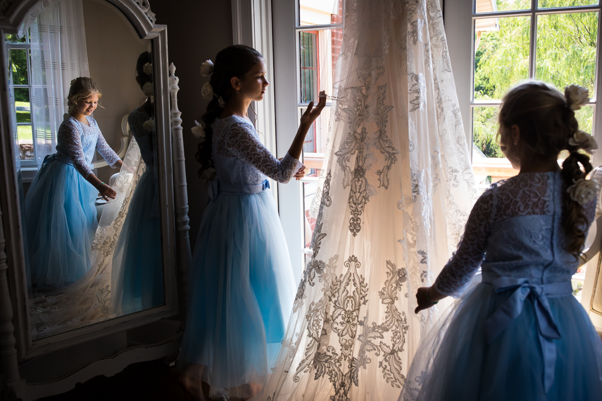 unique best wedding photographer Hershey pa two girls touching bride's wedding dress wearing blue dresses