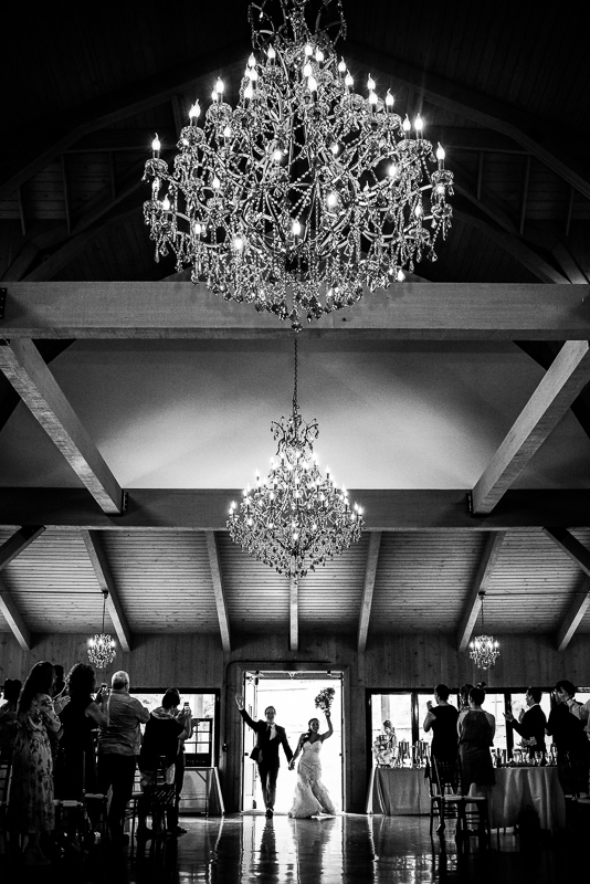 best historic acres of Hershey wedding photographer black and white photo of large chandelier hanging with bride and groom being announced as husband and wife into reception