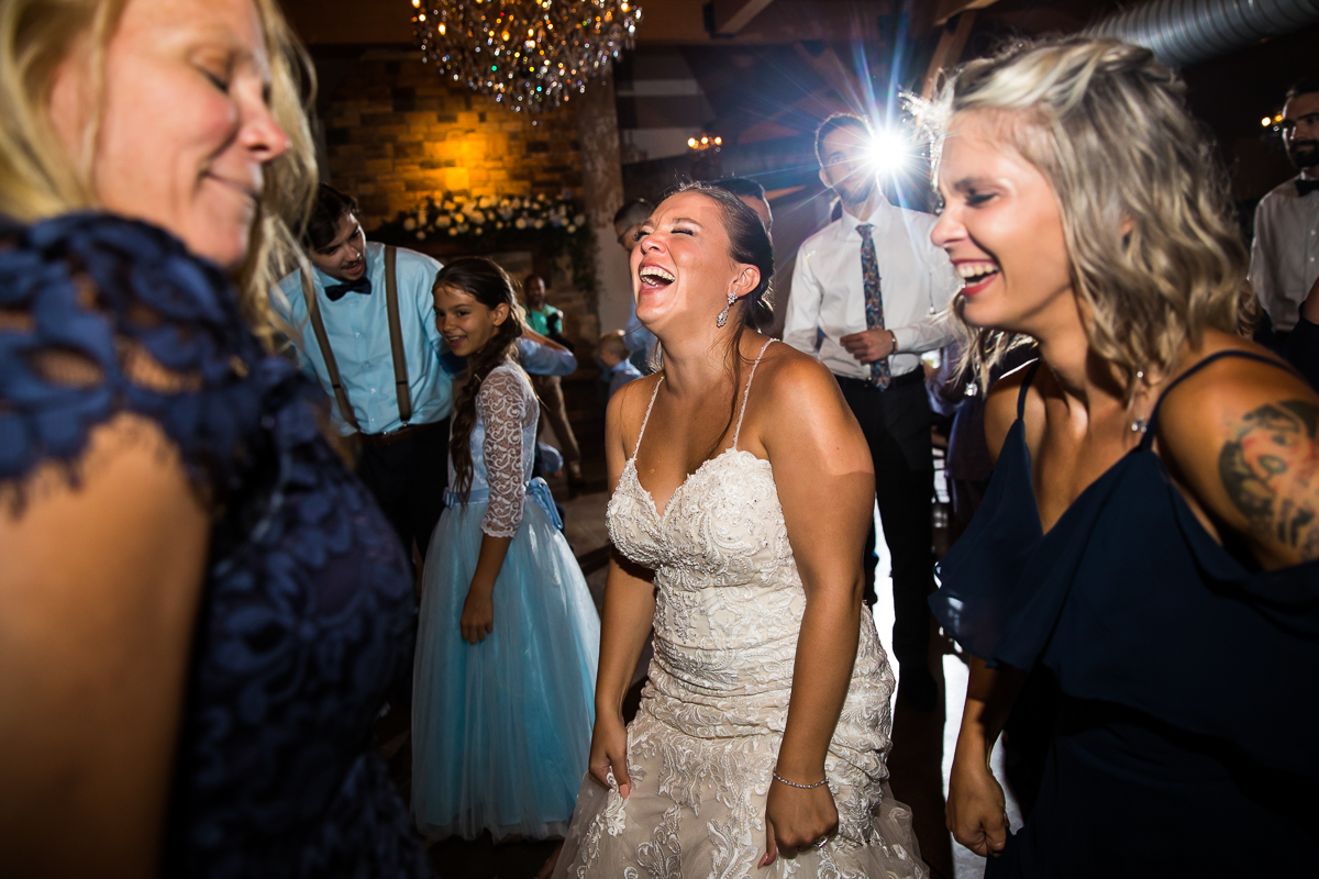 authentic candid best wedding photographer pa bride laughs while dancing with guests during wedding reception