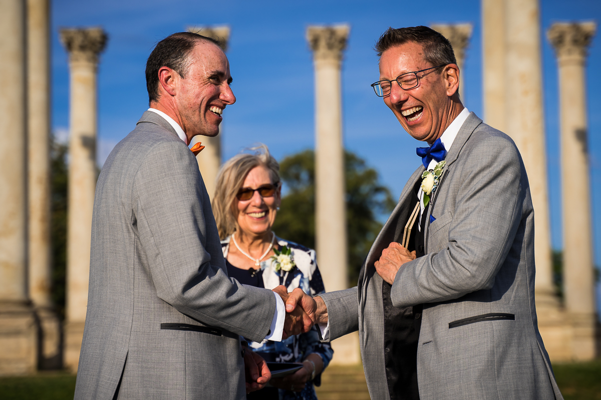 authentic candid best wedding photographer central PA DC two grooms shake hands during wedding vows in front of National Capitol Columns national arboretum wedding photographer
