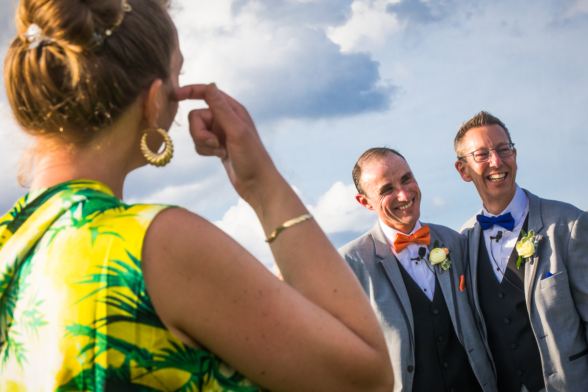colorful candid wedding photographer DC central PA two grooms smile at guests while officiant stands to the side