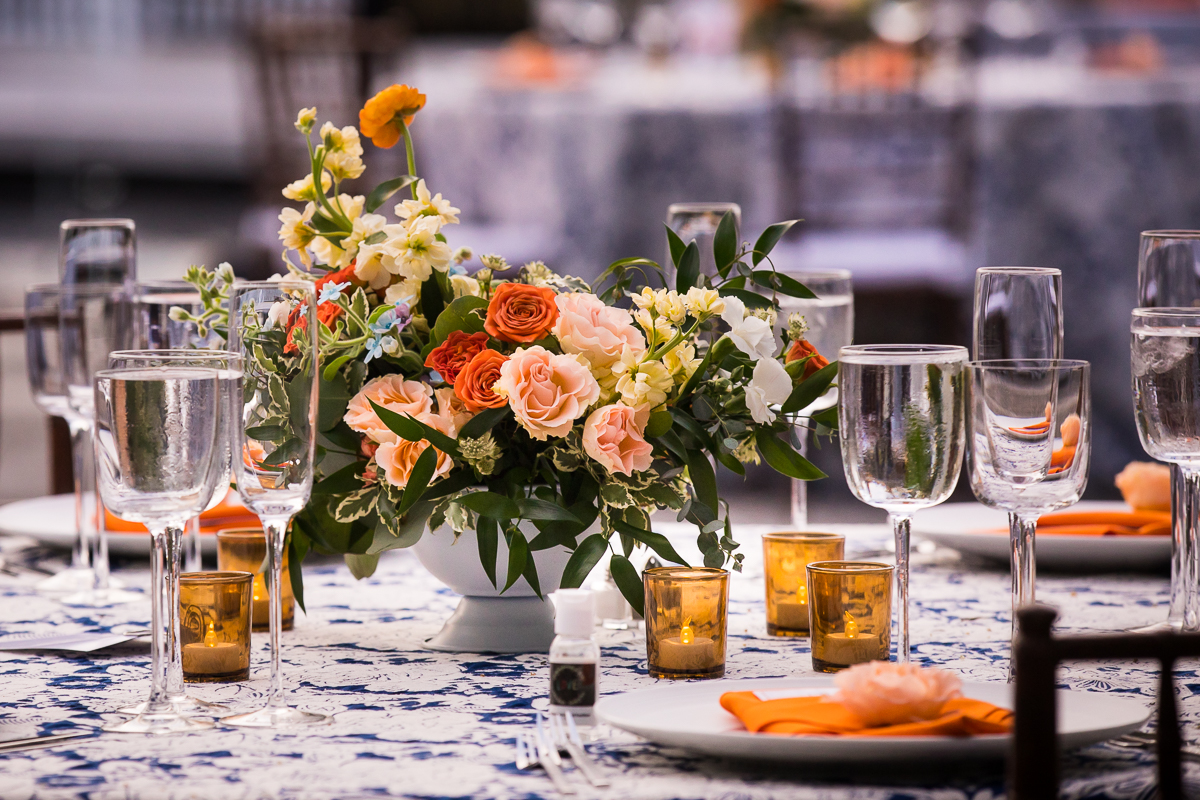 vibrant colorful best wedding photographer national arboretum wedding decor orange and blue flower centerpieces with blue printed tablecloths and orange napkins amber candles