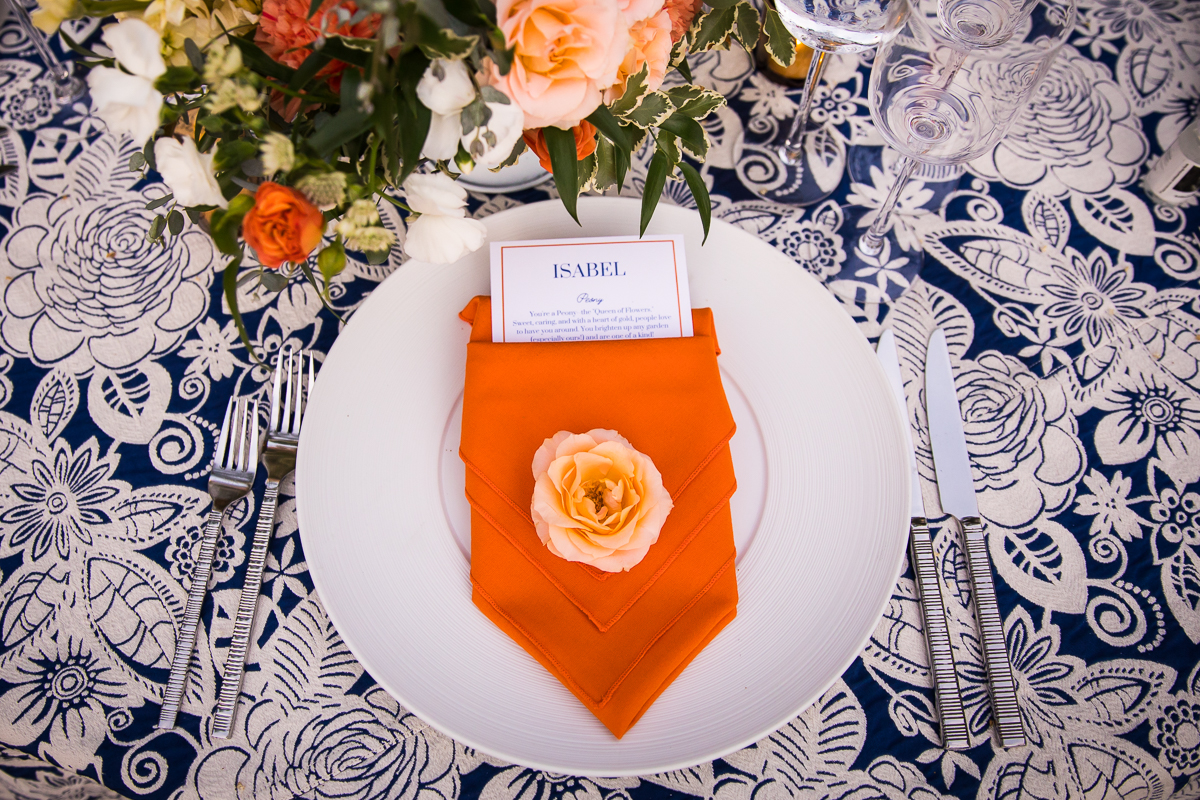 national arboretum wedding place settings orange napkins on white plates with flower on top of personalized menu cards with blue floral tablecloth