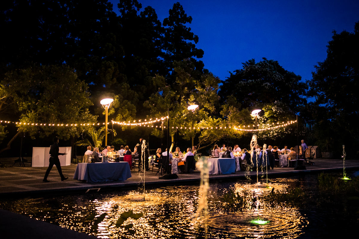 colorful creative blue hour wedding photographer national arboretum DC wedding reception with fountain in background guests eat amongst string lights outside early summer wedding