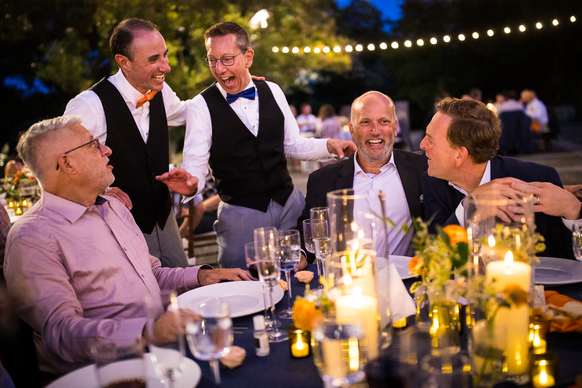 best candid authentic DC wedding photographer national arboretum wedding reception on patio grooms chat and laugh with guests during dinner