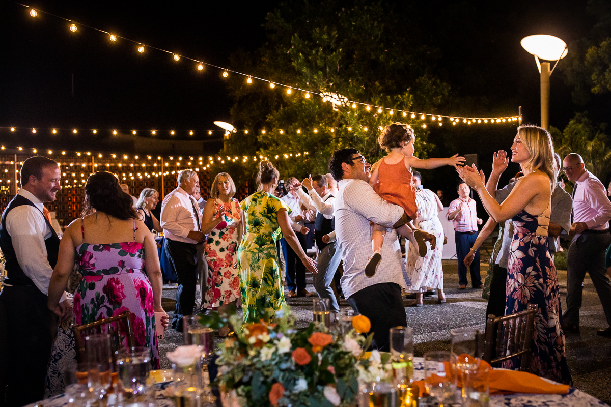 candid colorful best wedding photographer national arboretum reception guests smiling and dancing with string lights above them