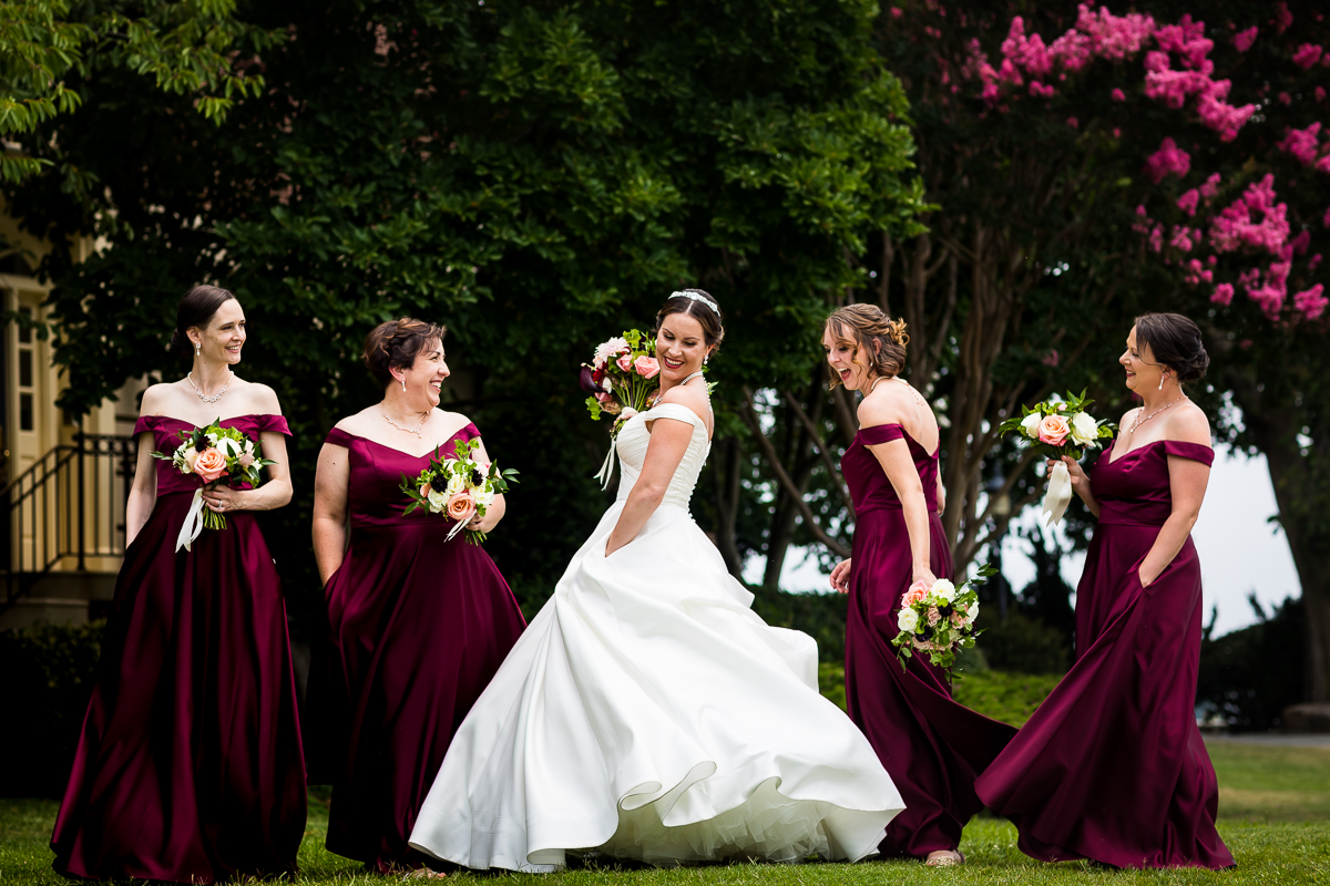 best authentic candid colorful dc wedding photographer bride wearing wedding dress with pockets twirls while bridesmaids wearing burgundy dresses smile
