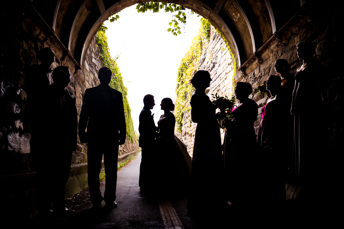 Wilkes street tunnel wedding photographer bride and groom stand looking at each other silhouetted against outside with wedding party near