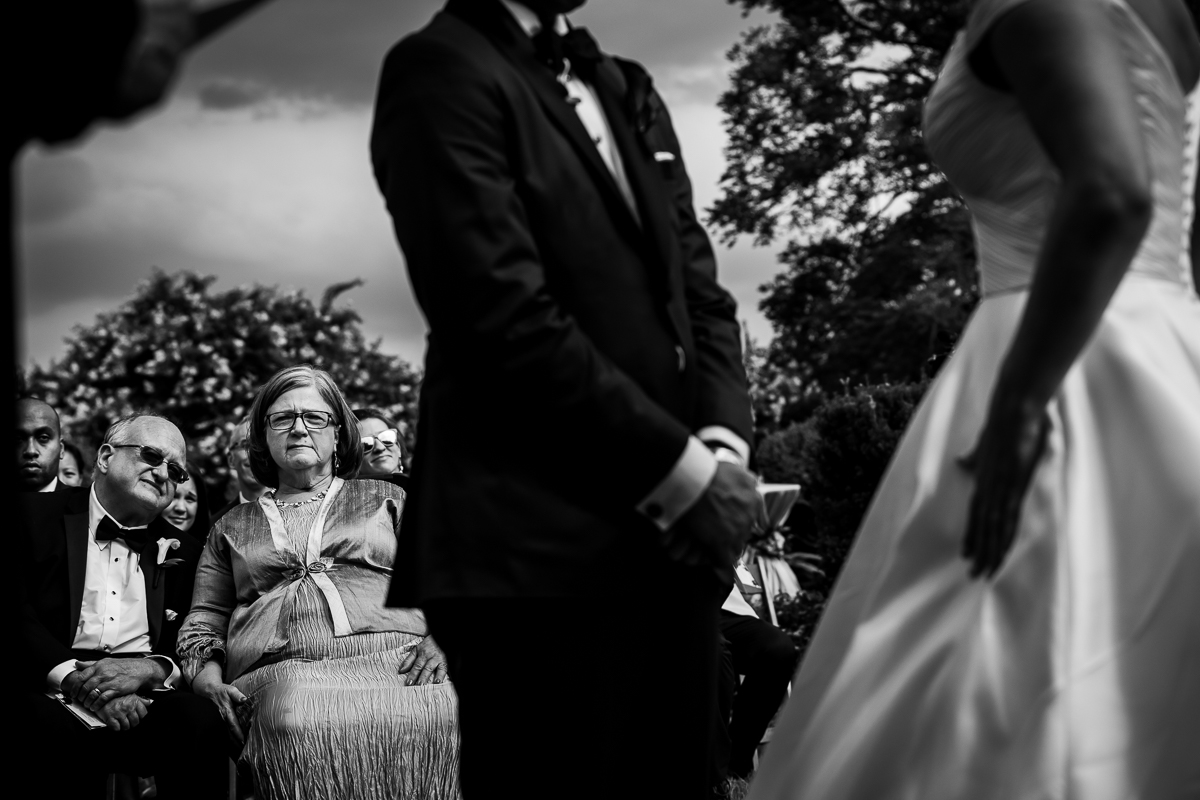 unique artistic wedding photographer grooms parents look on during wedding ceremony black and white photo