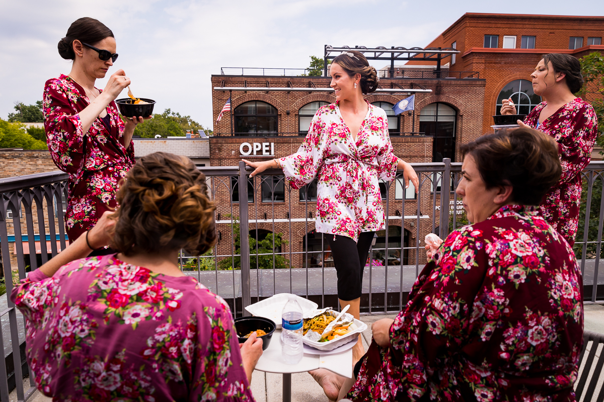 Kimpton Lorien Alexandria va hotel bridesmaids wear floral robes and eat food on balcony downtown during getting ready 
