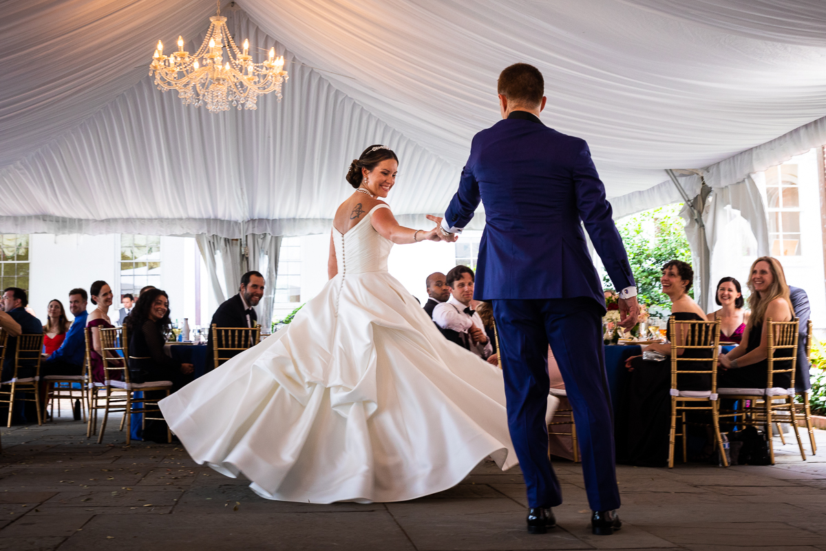 river farm wedding first dance bride twirls while groom holds her hand under reception tent