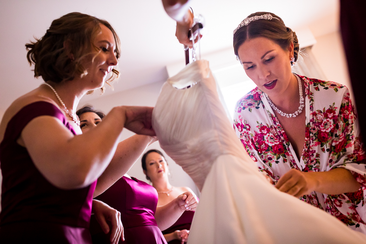 candid authentic creative wedding photographer dc bridesmaid helping bride with dress while getting ready