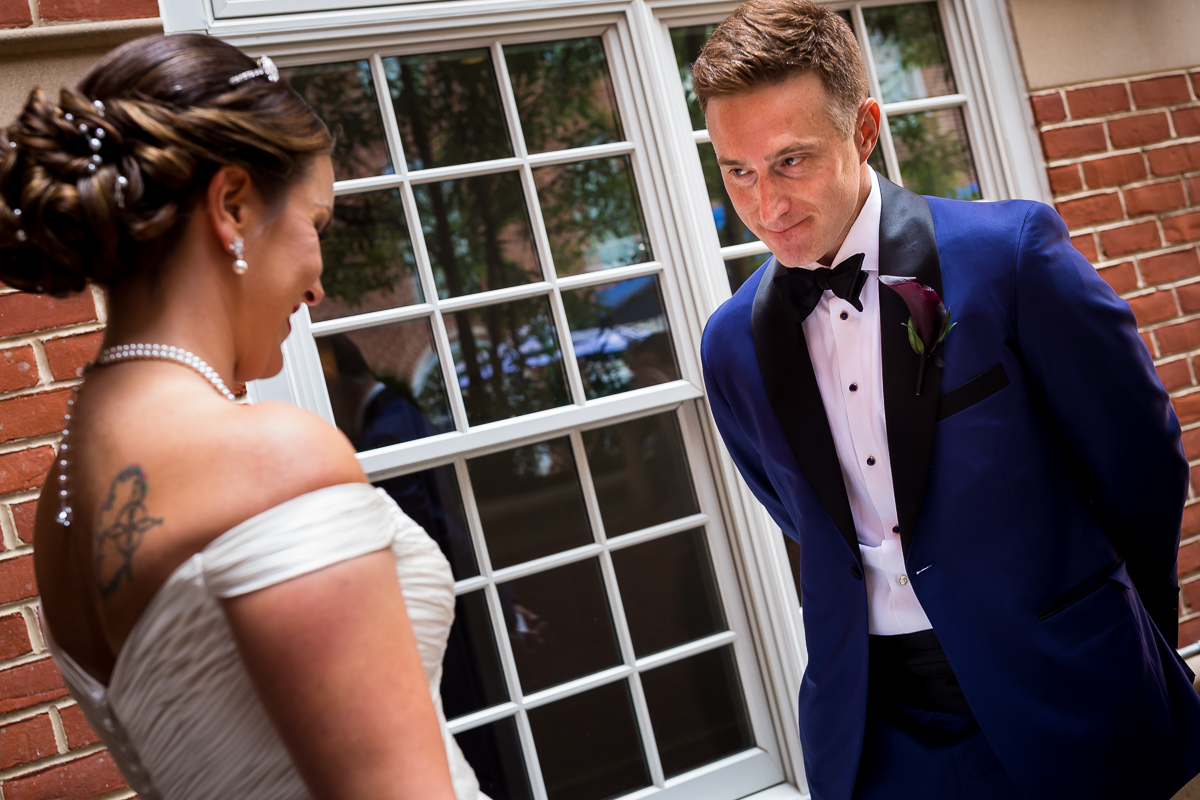 downtown va wedding photographer bride and groom smile at each other during first look outside Kimpton Lorien