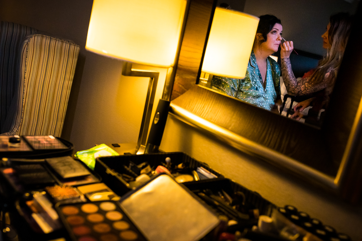 authentic candid Gettysburg wedding photographer bride getting makeup done with makeup all displayed in hotel room