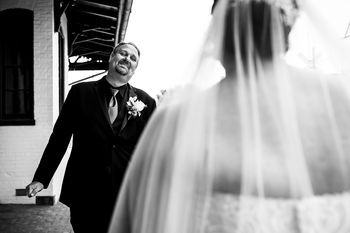emotional authentic best gettysburg wedding photographer groom smiles while seeing bride for first time during first look black and white photo