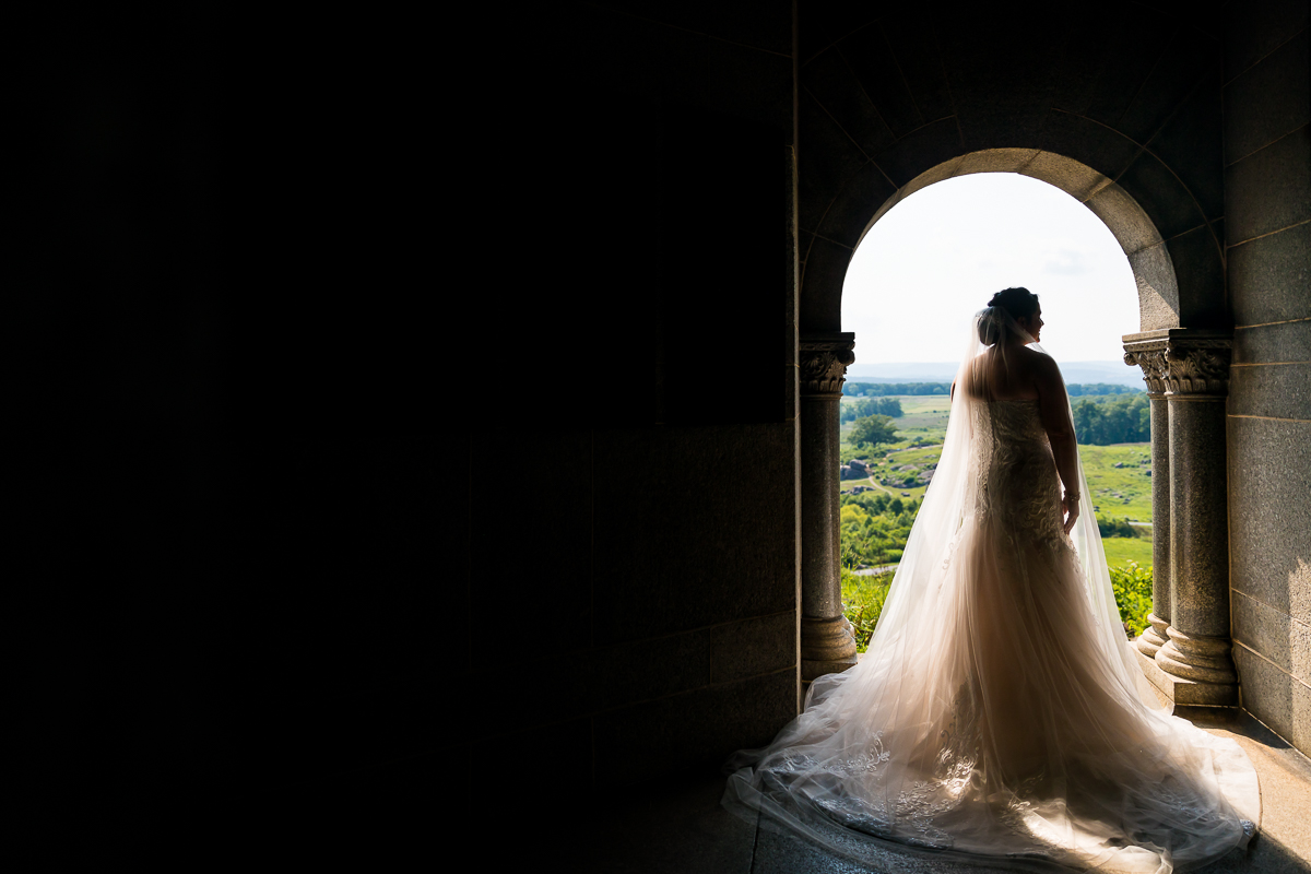 creative artistic unique bridal portrait bride standing in arch at little round top looking out at beautiful view
