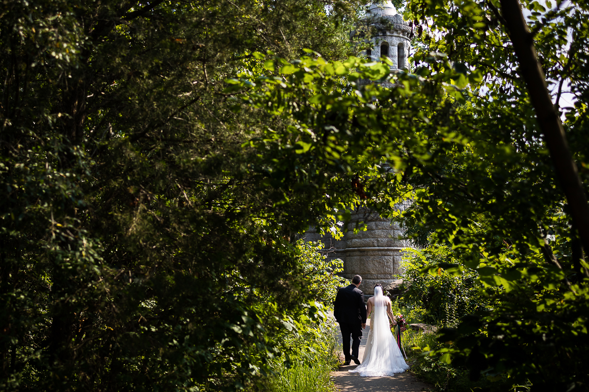 best little round top wedding photographer bride and groom walking hand in hand to monument with forest surrounding them