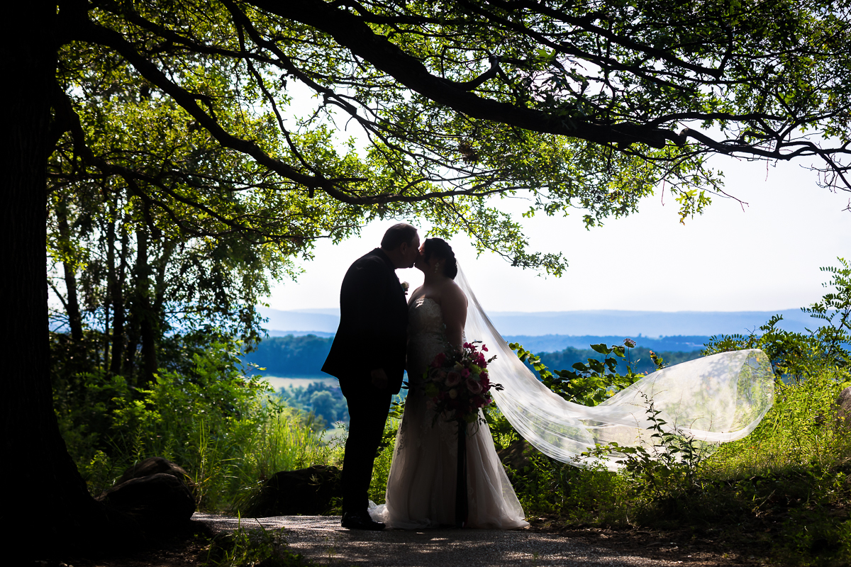 colorful vibrant best wedding photographer bride and groom share a kiss on top of little round top with beautiful scenery behind