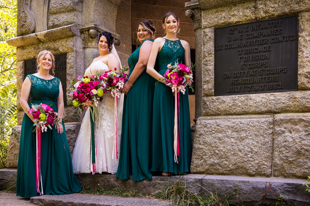 bridesmaids wearing emerald green dresses holding pink floral bouquets standing next to bride at little round top 