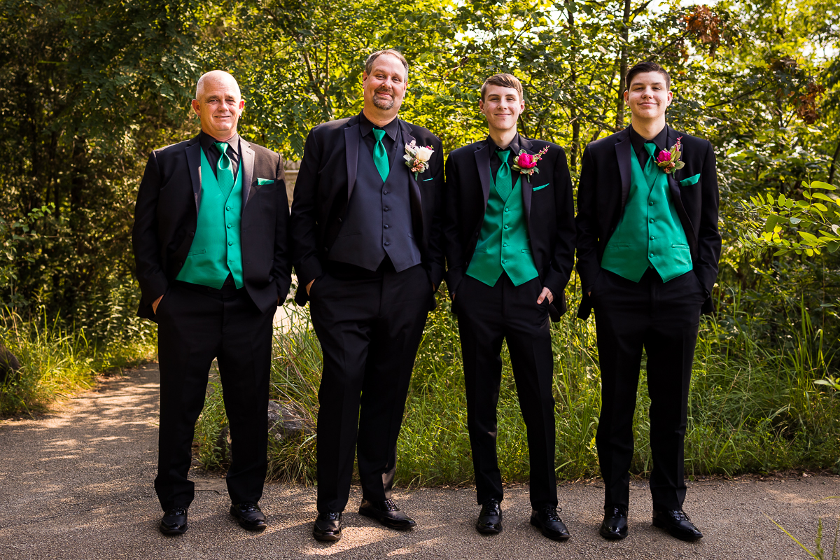 groom and groomsmen standing smiling at camera wearing emerald green vests