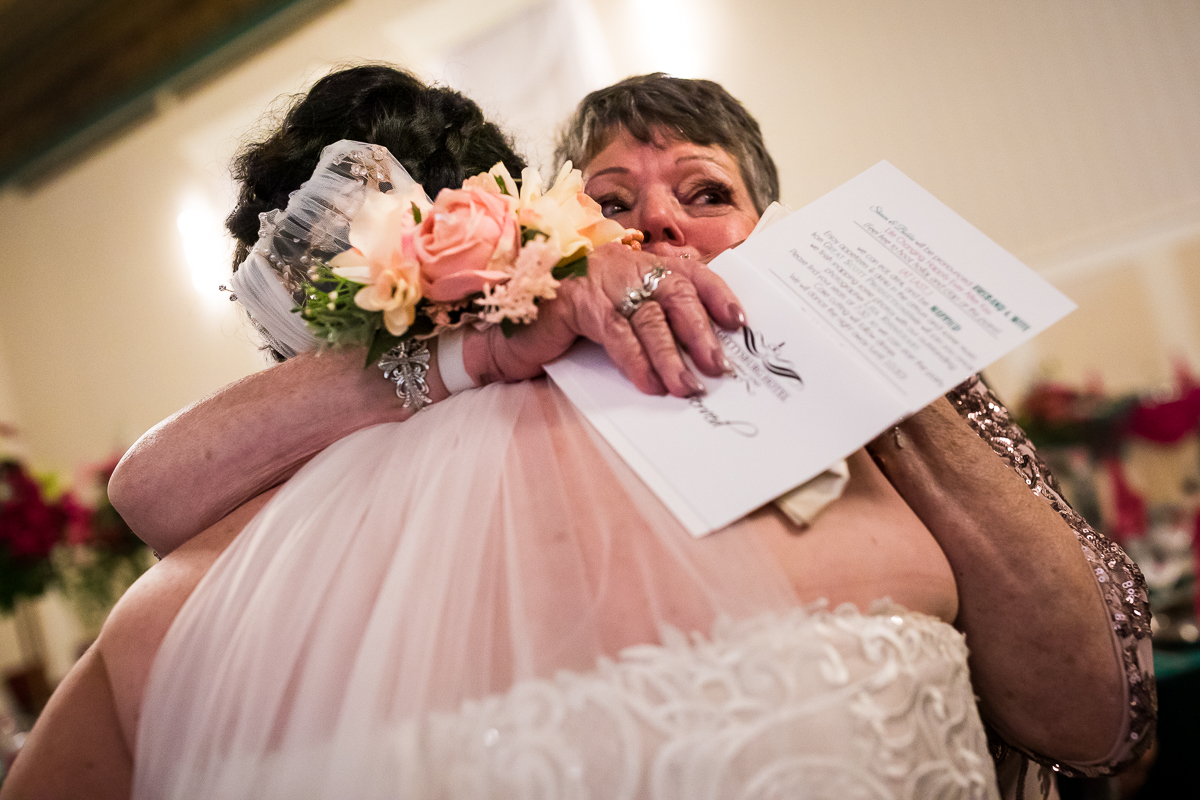 bride shares emotional moment with guest after ceremony hugging and tears in eyes emotional candid wedding photographer